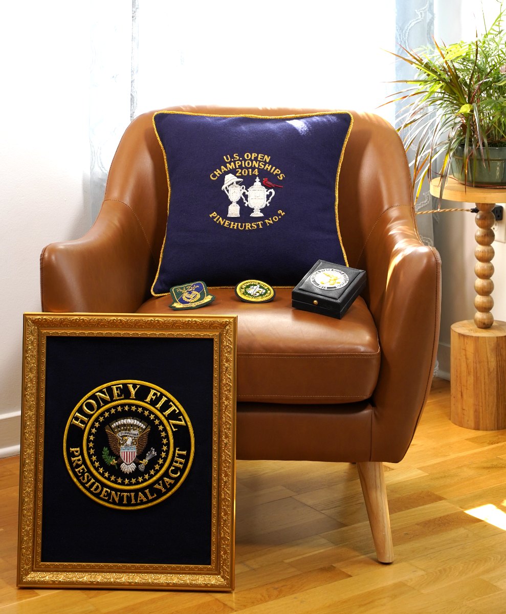 Framed presidential yacht crest, a crested cushion and club badges in a sitting room